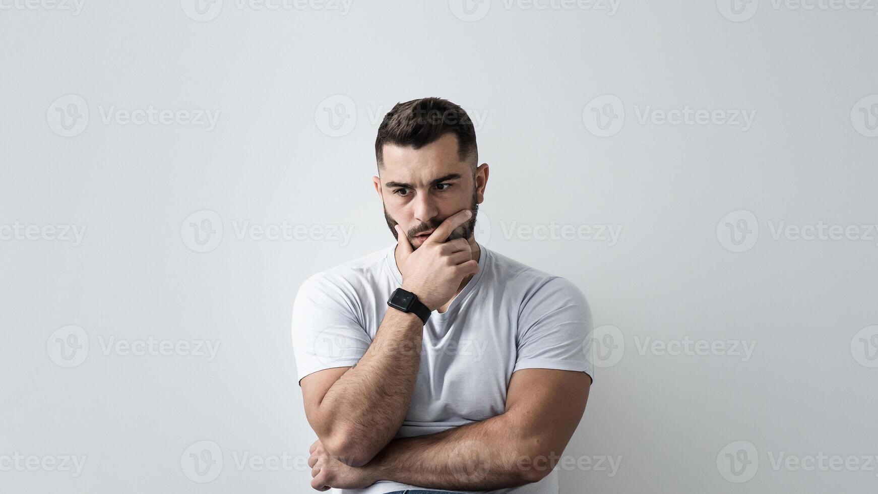 Young depressed man sit against gray wall at home feeling unhappy, lonely and sad in depression, mental health. Concentrated serious shocked attractive muscular bearded guy on floor and pondering photo