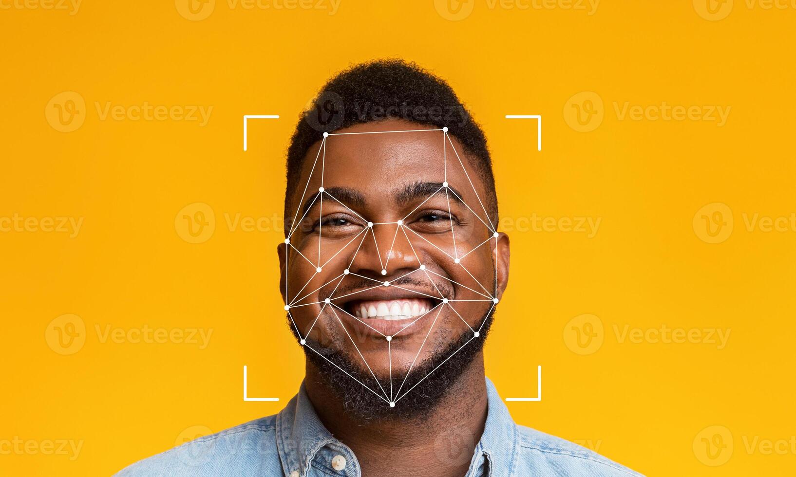 A young man with a cheerful smile is captured against a vibrant yellow background. Facial recognition markers overlay his face, highlighting the technology's application in identification. photo