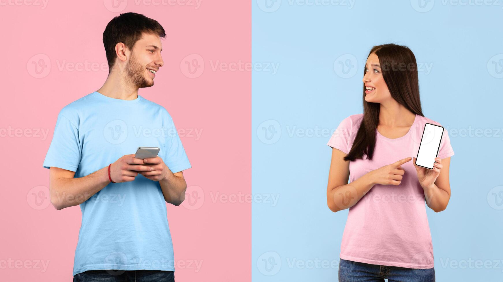 Look At It. Portrait of woman holding and pointing at white blank cellphone screen over yellow and blue studio background. Girlfriend showing empty touchscreen template for mockup to her boyfriend photo