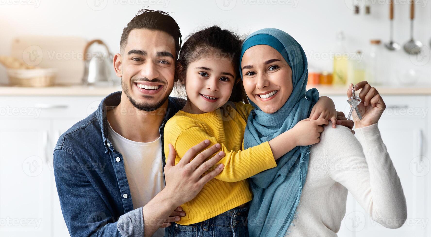 Family Housing Concept. Happy Islamic Spouses With Little Daughter Holding Home Keys In Hands And Smiling At Camera, Cheerful Arab Parents And Their Female Child Celebrating Moving, Closeup Shot photo