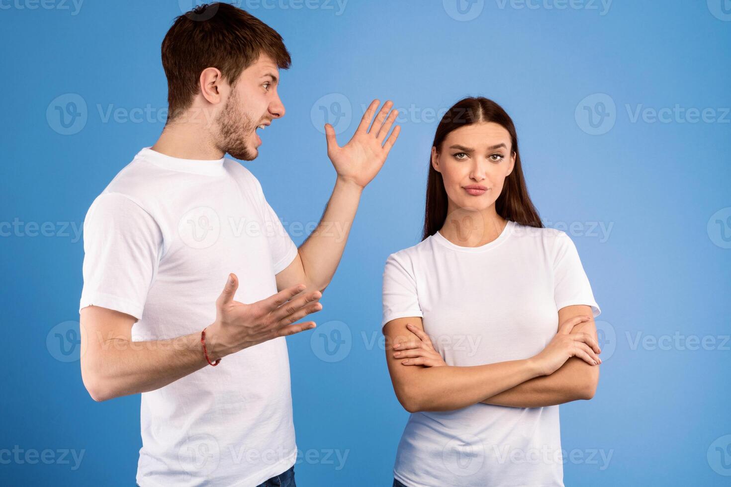 Relationship Problems. Young man arguing with his girlfriend who ignoring him, isolated over purple studio wall photo