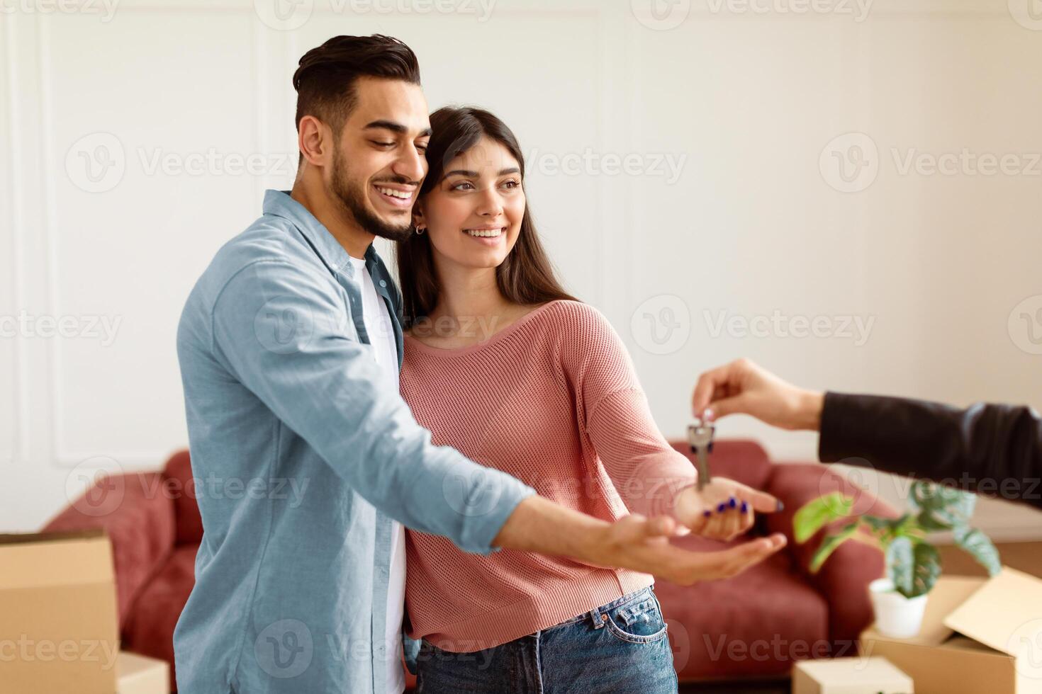 Buying New Apartment. Portrait of happy smiling couple taking key of future new house. Professional real estate agent holding in hand and giving keys to young millennial buyers. Mortgage Concept photo