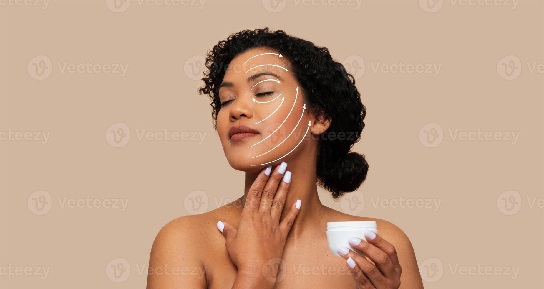 A woman practices self-care by applying skin care cream to her face. She enjoys a relaxing moment of beauty routine in a tranquil setting with neutral tones. photo