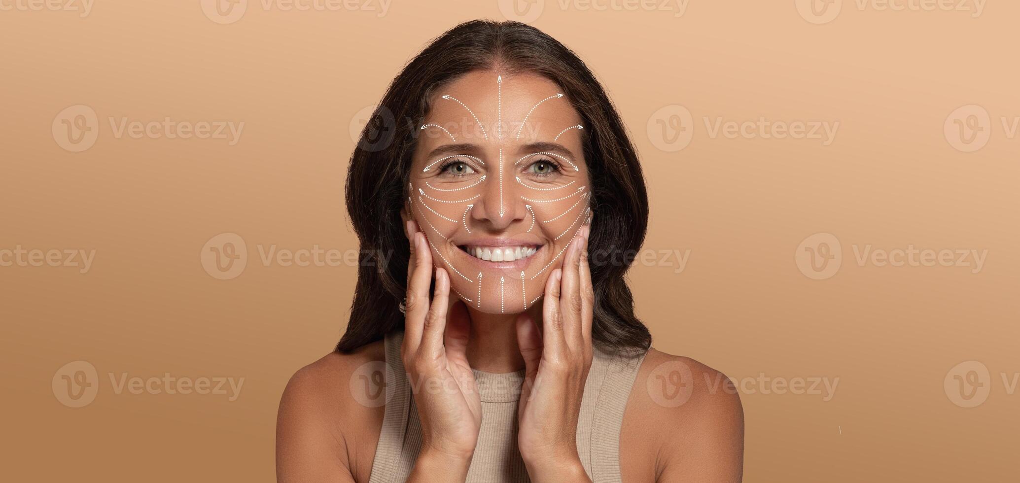 A woman is enjoying her skin care routine, smiling while applying products to her face. The softly lit background enhances the focus on her radiant skin and joyful expression, perfect for relaxation. photo