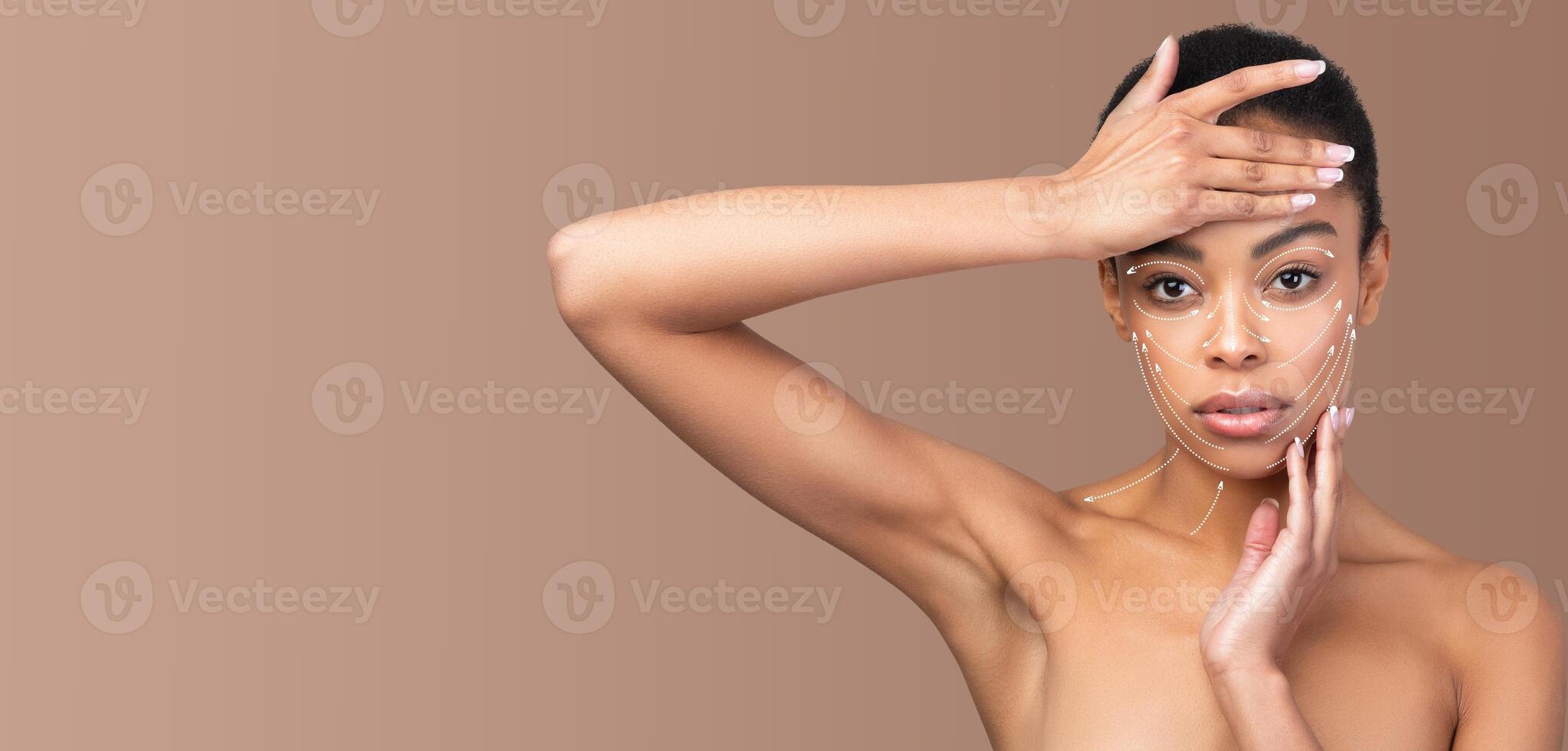 African American woman engages in a skin care routine, gently applying a pampering treatment to her face. Her skin glows while she poses in a serene, isolated setting with a calming background. photo