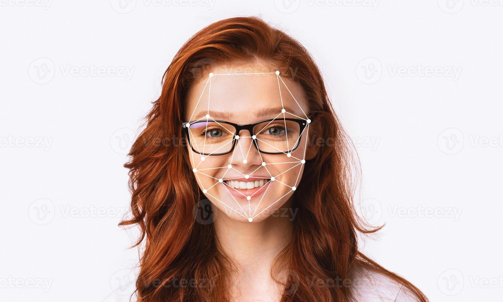 A young woman with red hair and glasses smiles while facial recognition technology tracks her features. The plain background emphasizes the focus on her expression and the technology. photo