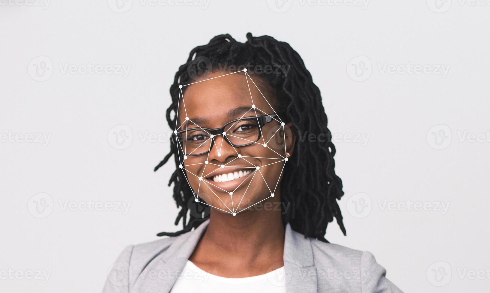 A woman with glasses and dreadlocks smiles at the camera. Facial recognition technology is used to identify distinct facial features against an empty background, emphasizing her expression. photo