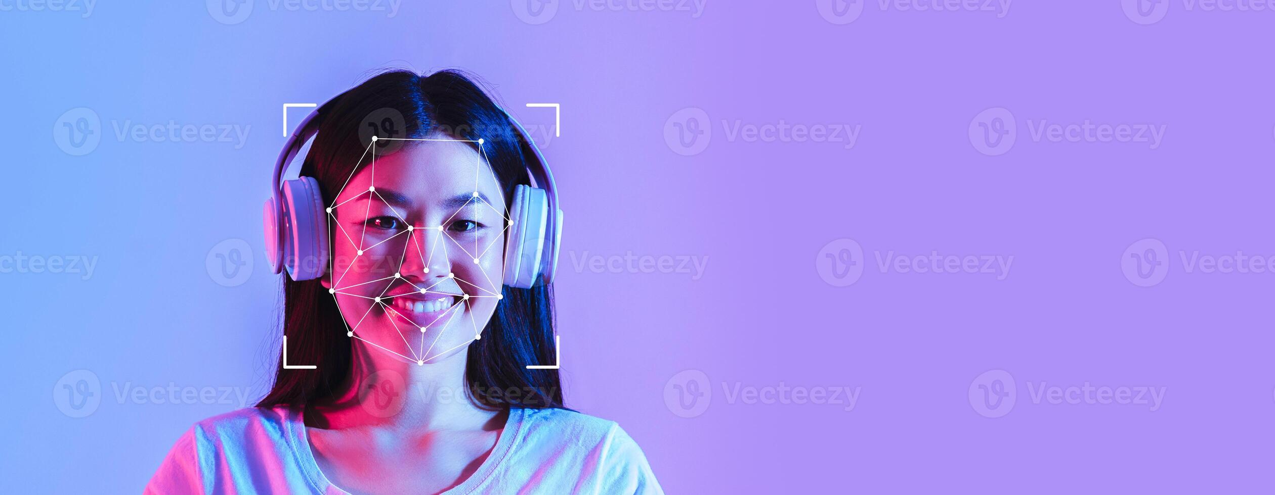 A young woman wearing headphones smiles while facial recognition technology scans her face against a colorful background. The setting emphasizes technology and modern identification methods. photo