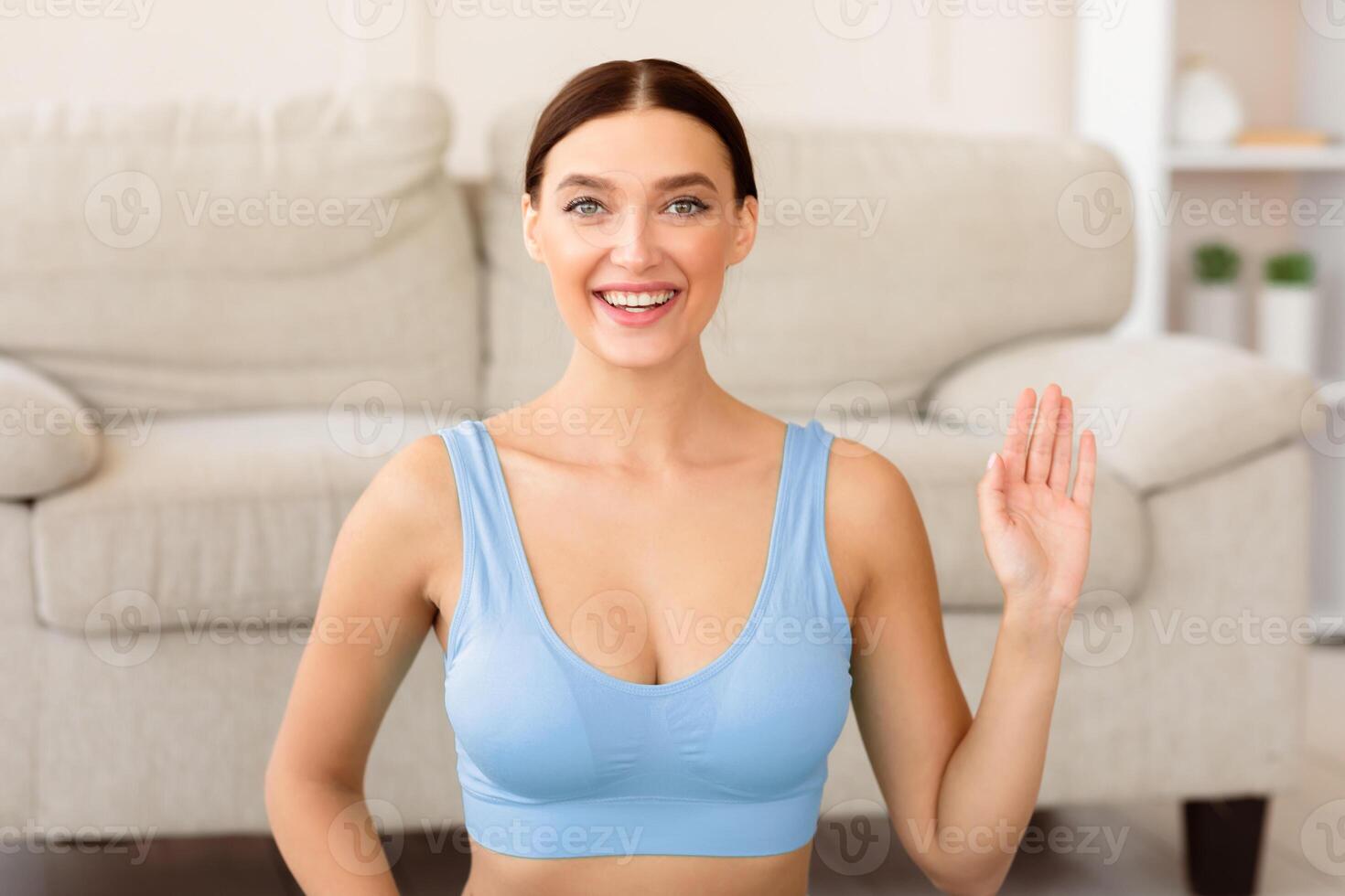 Home Training. Fitness Girl Waving Hello Smiling To Camera Exercising Sitting Indoors photo