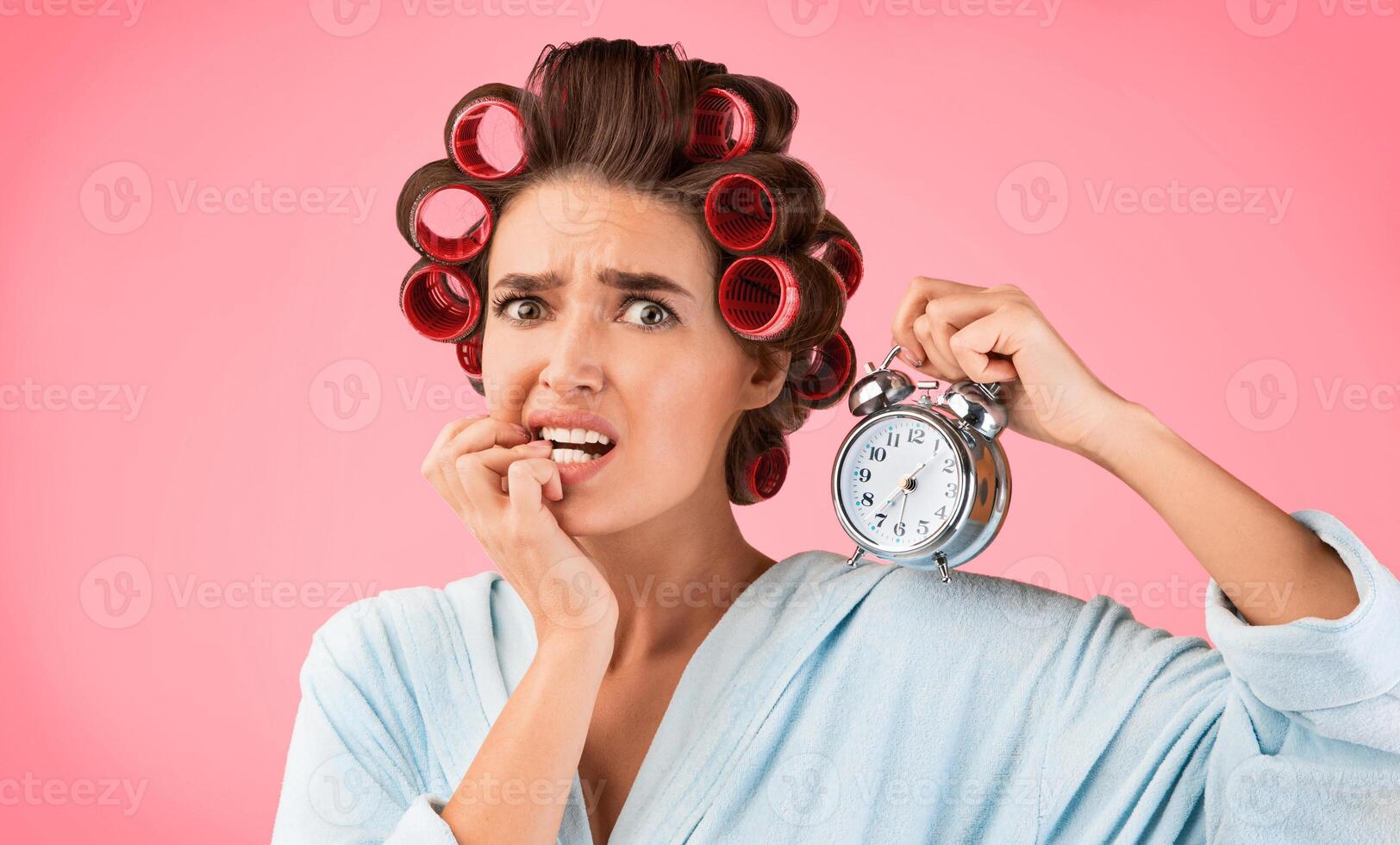 Anxiety Concept. Anxious Housewife Holding Clock Biting Fingers Standing Over Yellow Background In Studio photo
