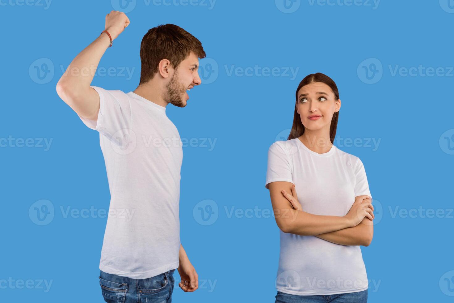 Relationship Problems. Young man trying to hit his girlfriend who ignoring him, isolated over purple studio wall photo