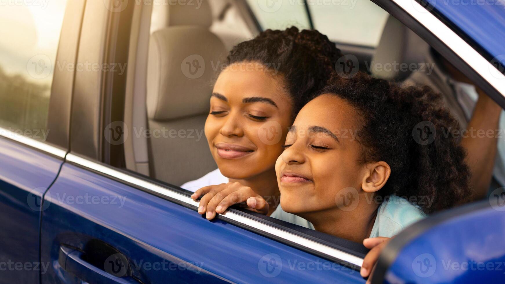 Joyful Black Mother And Daughter Sitting In Automobile, Enjoying Road Trip Smelling Fresh Air In Opened Window, Family Having Summer Adventure Traveling By Car. Transportation Concept photo