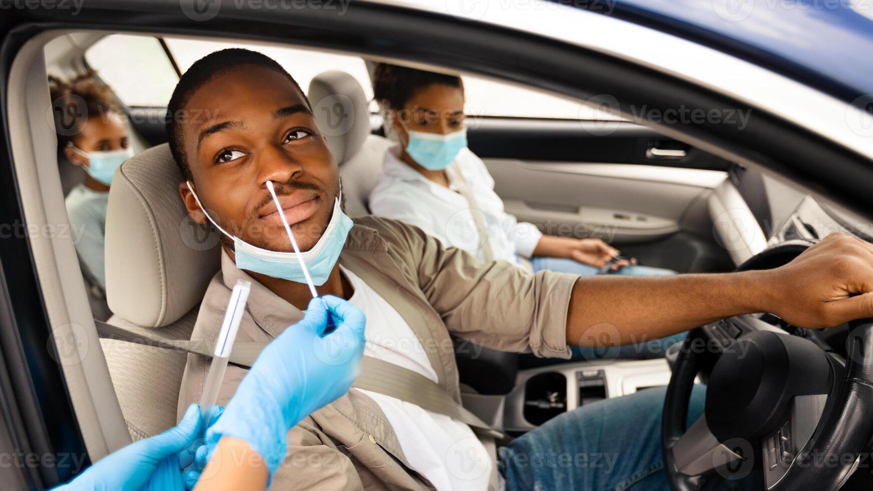 African American Man Getting Tested For Coronavirus In Car, Driving Traveling With Family By Auto. Unrecognizable Medical Worker Making PCR Test For Male Driver. Covid-19 Pandemic Concept photo