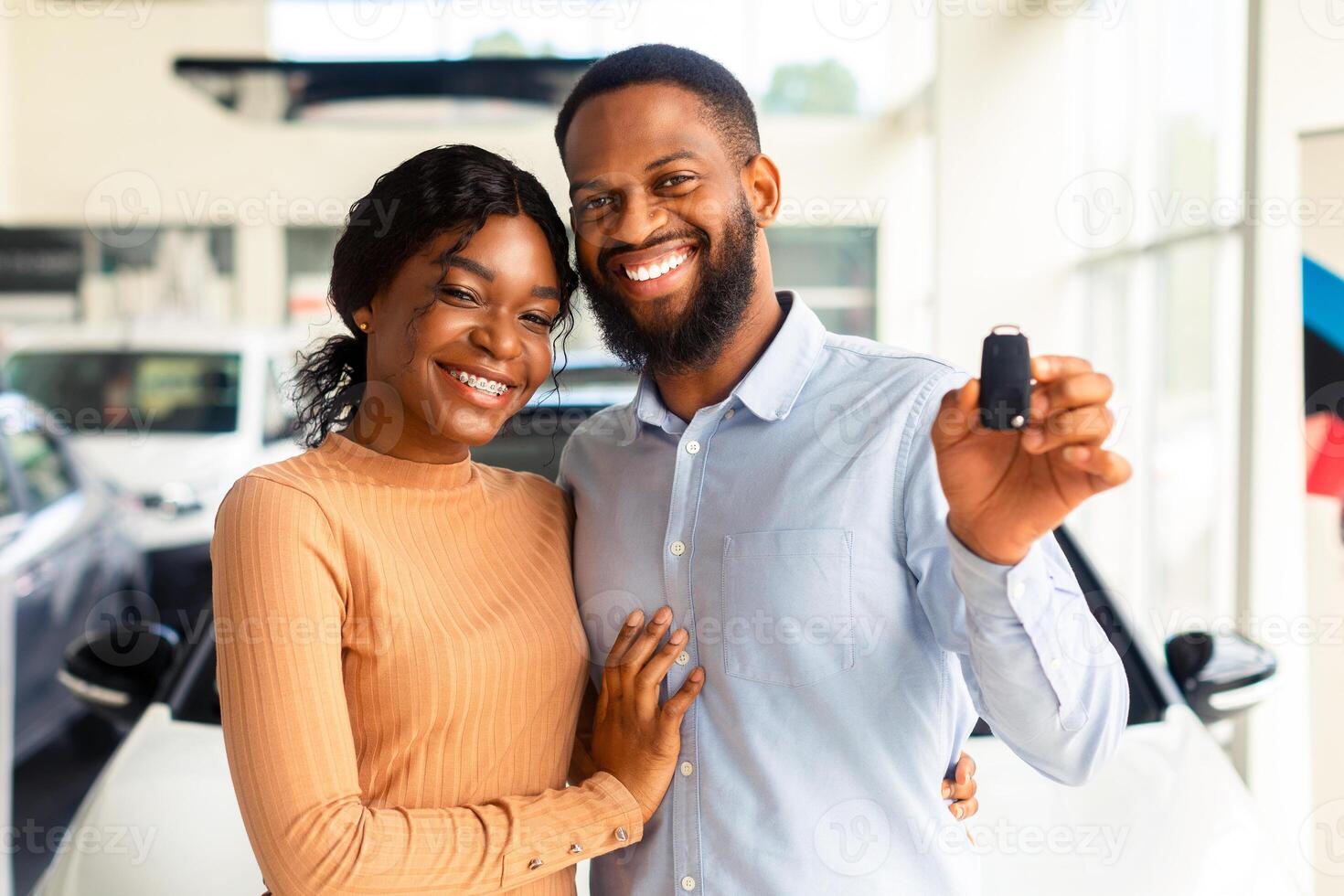 Happy Car Owners. Portrait Of Young Black Couple With Automobile Keys In Hands Posing In Modern Dealership Center After Purchasing Their Own Vehicle, African American Family Smiling At Camera photo