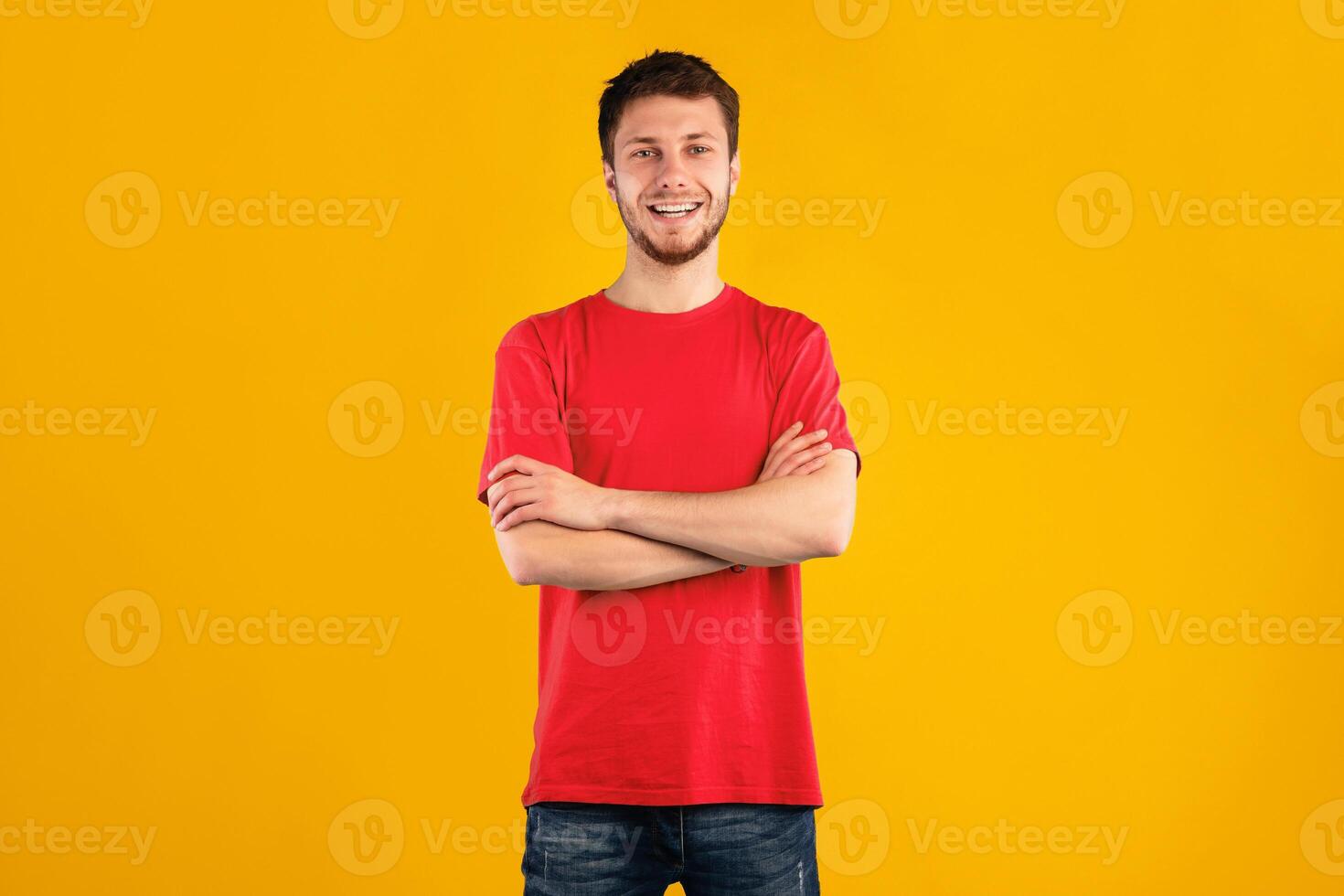 Portrait of happy bearded guy smiling, looking at camera and posing with folded arms isolated over blue studio background. Confident caucasian man crossing hands, expressing positive emotions photo