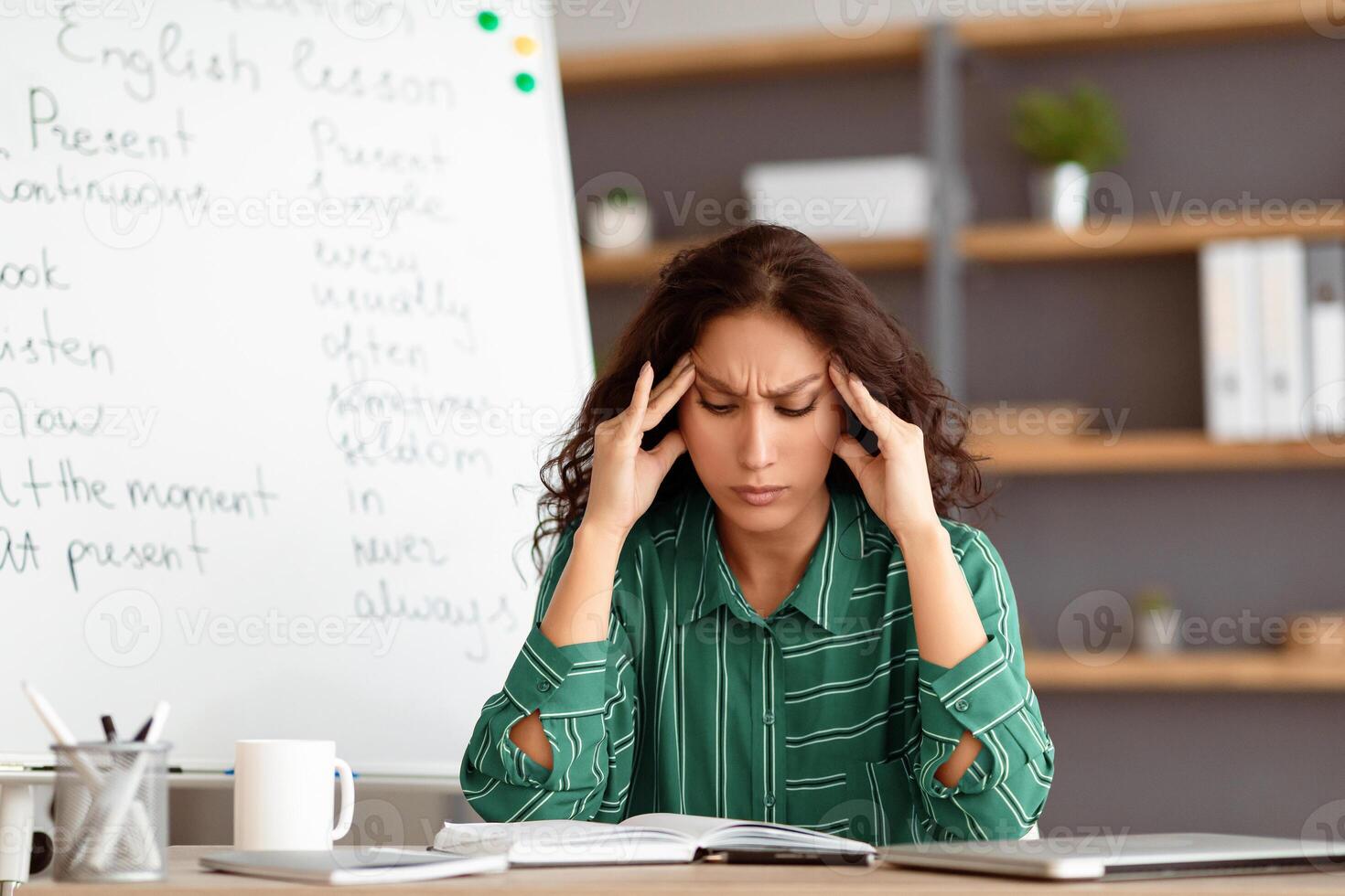 Tired From Work. Portrait of exhausted stressed young woman suffering from headache, touching and massaging her forehead and temples, sitting at desk near whiteboard, thinking about problems photo