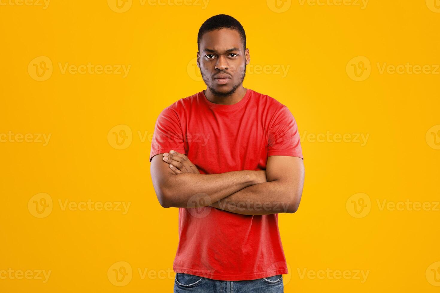 Serious African American Man Posing Crossing Hands Looking At Camera Frowning Expressing Negative Emotions Standing Over Yellow Background. Studio Shot. Male Emotional Blockage Problem photo