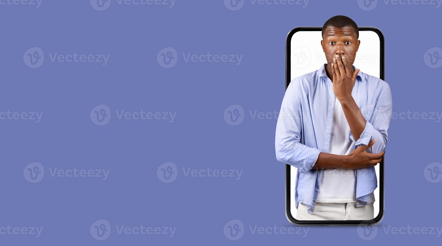 A man appears shocked while interacting with a smartphone featuring a large screen. He covers his mouth, expressing surprise. Bright, isolated background emphasizes the focus on his reaction. photo