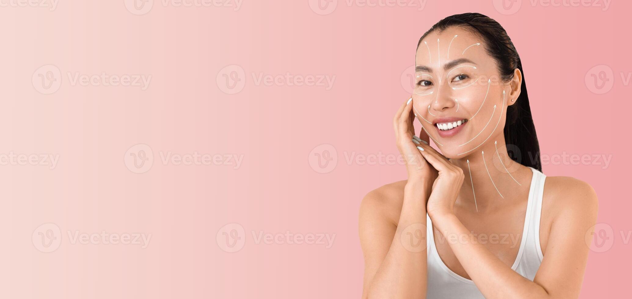 Asian woman enjoys her skincare routine, gently applying products to her face with a radiant smile. The soft pastel background enhances her beauty, creating a serene atmosphere for self-care. photo