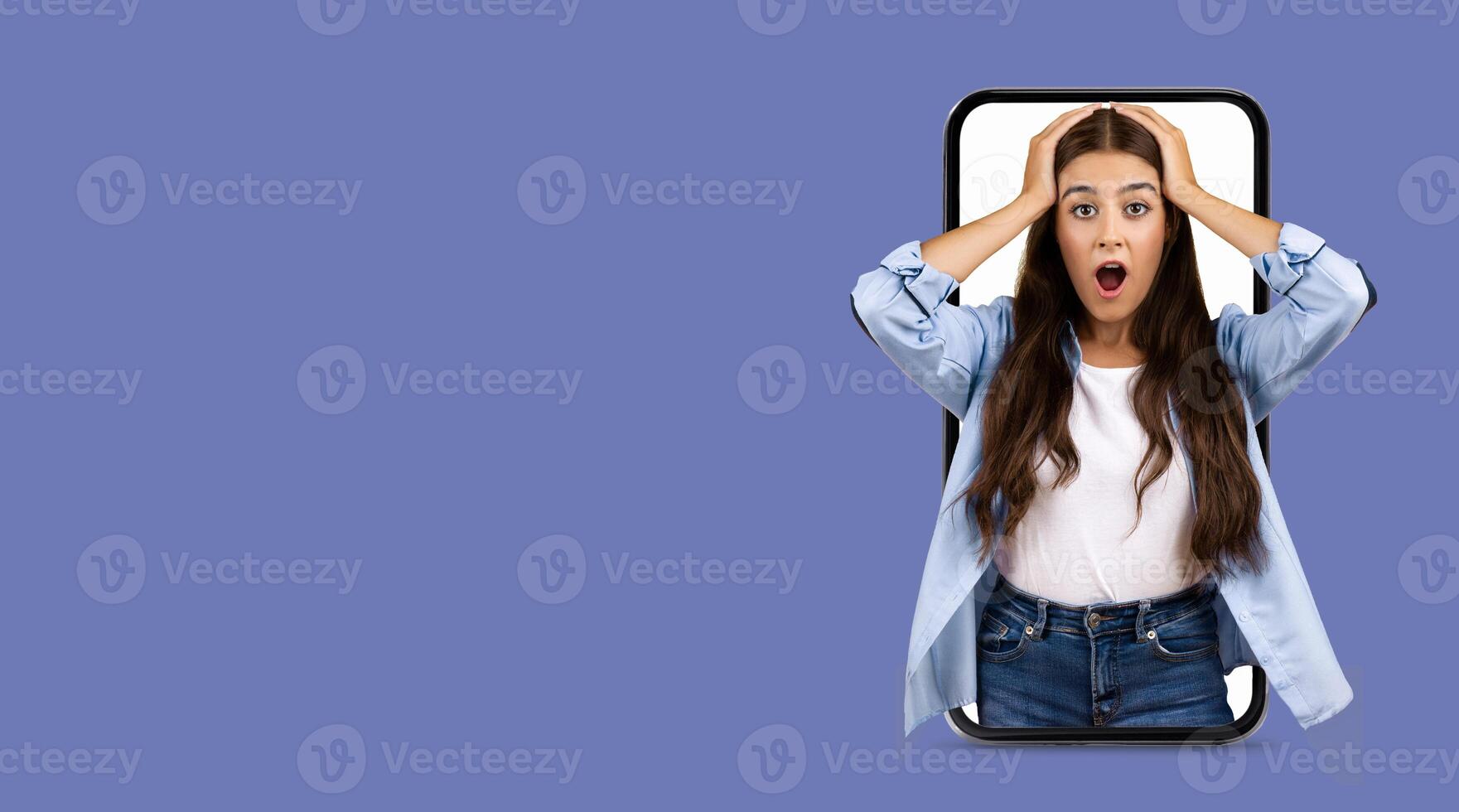A young woman shows an expression of shock and disbelief while using a large smartphone. She seems engaged with an online application, highlighting modern communication. photo