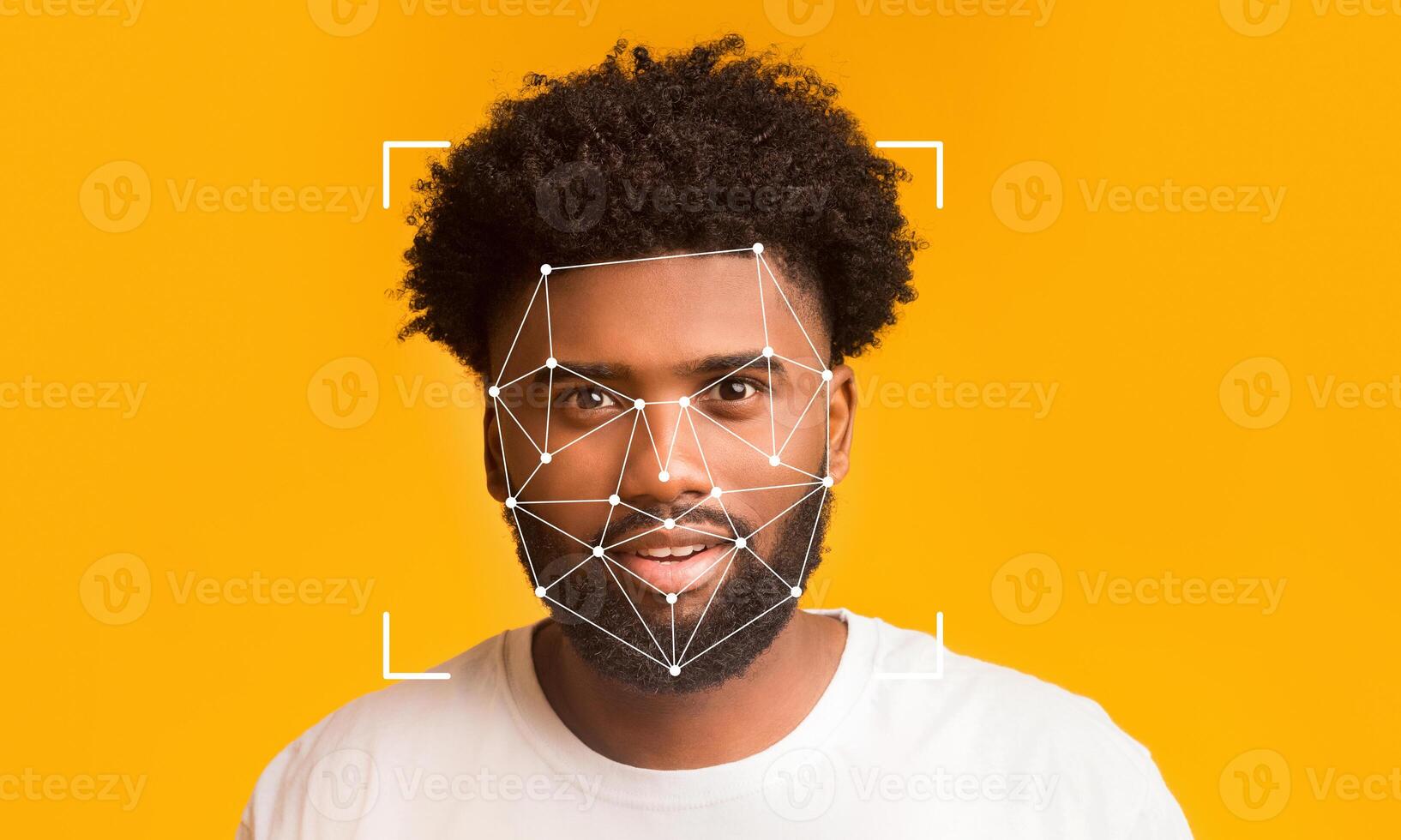 A young man with curly hair smiles while facial recognition technology analyzes his features against a bright yellow background. The digital overlay showcases points of identification. photo