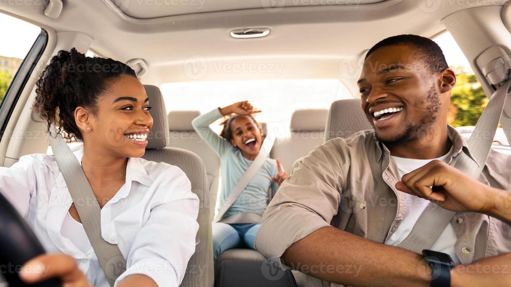 Happy African American Family Riding New Automobile And Having Fun Singing Enjoying Road Trip On Vacation. Parents And Daughter Traveling By Car On Weekend. Selective Focus photo