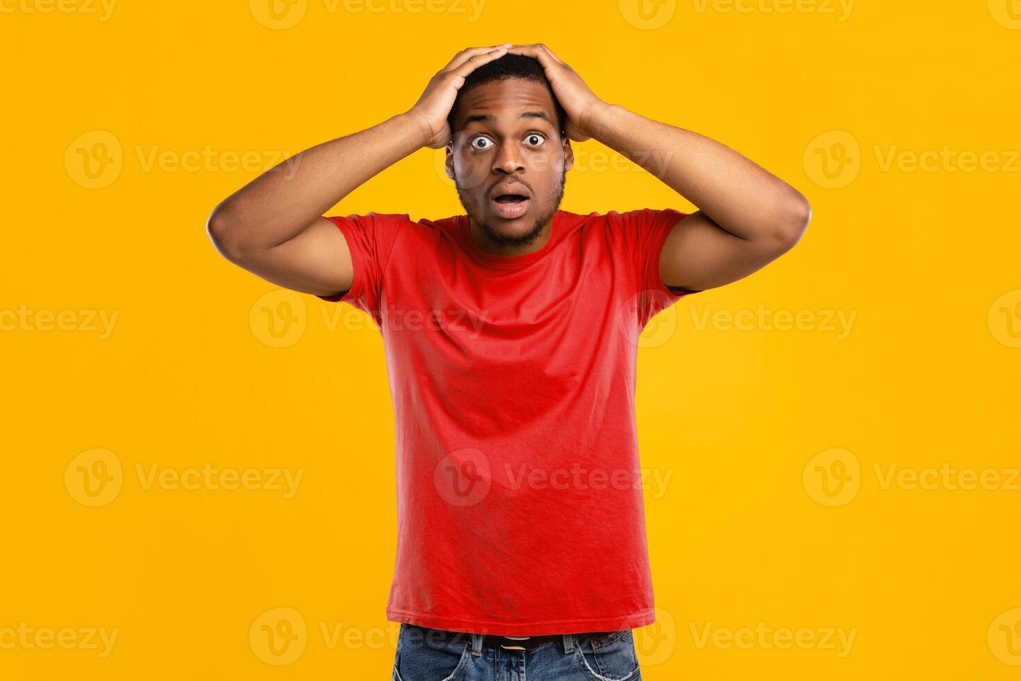 Omg. Black Man Touching Head In Shock Looking At Camera In Surprise Posing Standing Over Yellow Background In Studio, Wearing Bright T-Shirt. Shocking News, Human Emotions Concept photo