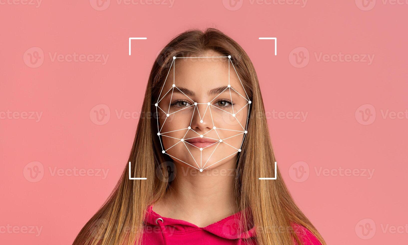 A young woman stands confidently in front of a pink backdrop, her face marked by facial recognition technology. The design features connecting lines and points highlighting facial features. photo