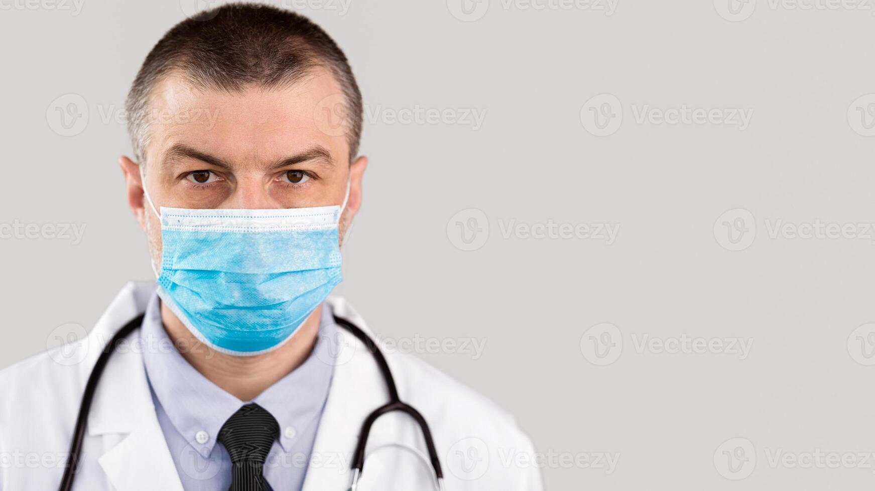 Profession and Medicine Concept. Close up of male doctor or scientist in protective facial mask over white background photo