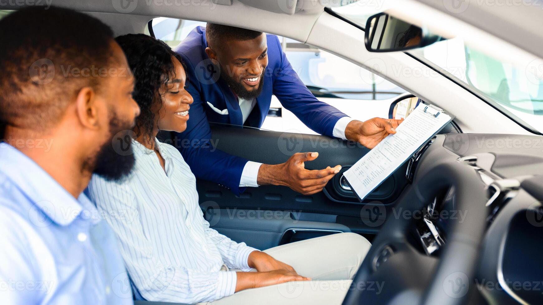 Young Black Couple Sitting Inside New Car In Showroom, Listening Professional Salesman, Excited African American Family Buying Own Automobile In Dealership Center, Choosing Vehicle Complectation photo