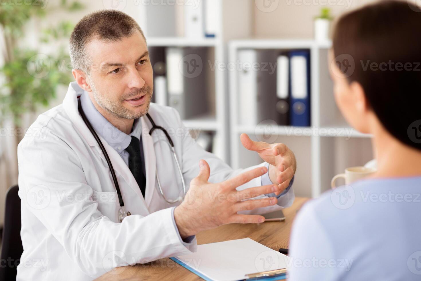 Medicine And Health Care Concept. Doctor and patient discussing something, sitting at the table, gesturing photo