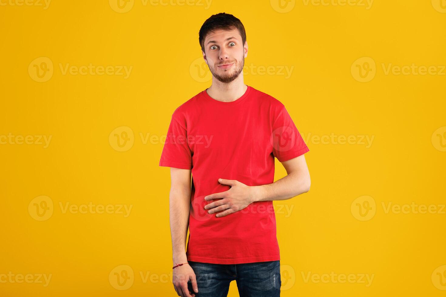 Pleasant Feeling In Stomach. Satisfied smiling young man keeping hand on belly, being in good mood after eating delicious meal, demonstrating that he is full, isolated over blue background photo