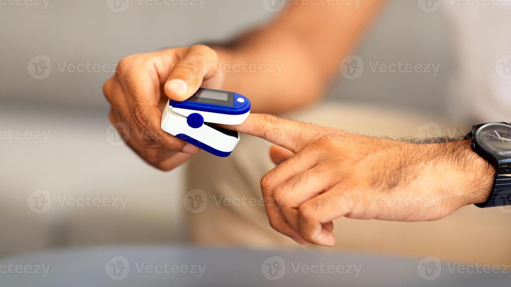 Unrecognizable man using modern pulse oximeter, closeup photo, copy space. Cropped of male patient putting clip-like small device for blood oxygen, saturation measuring and coronavirus photo