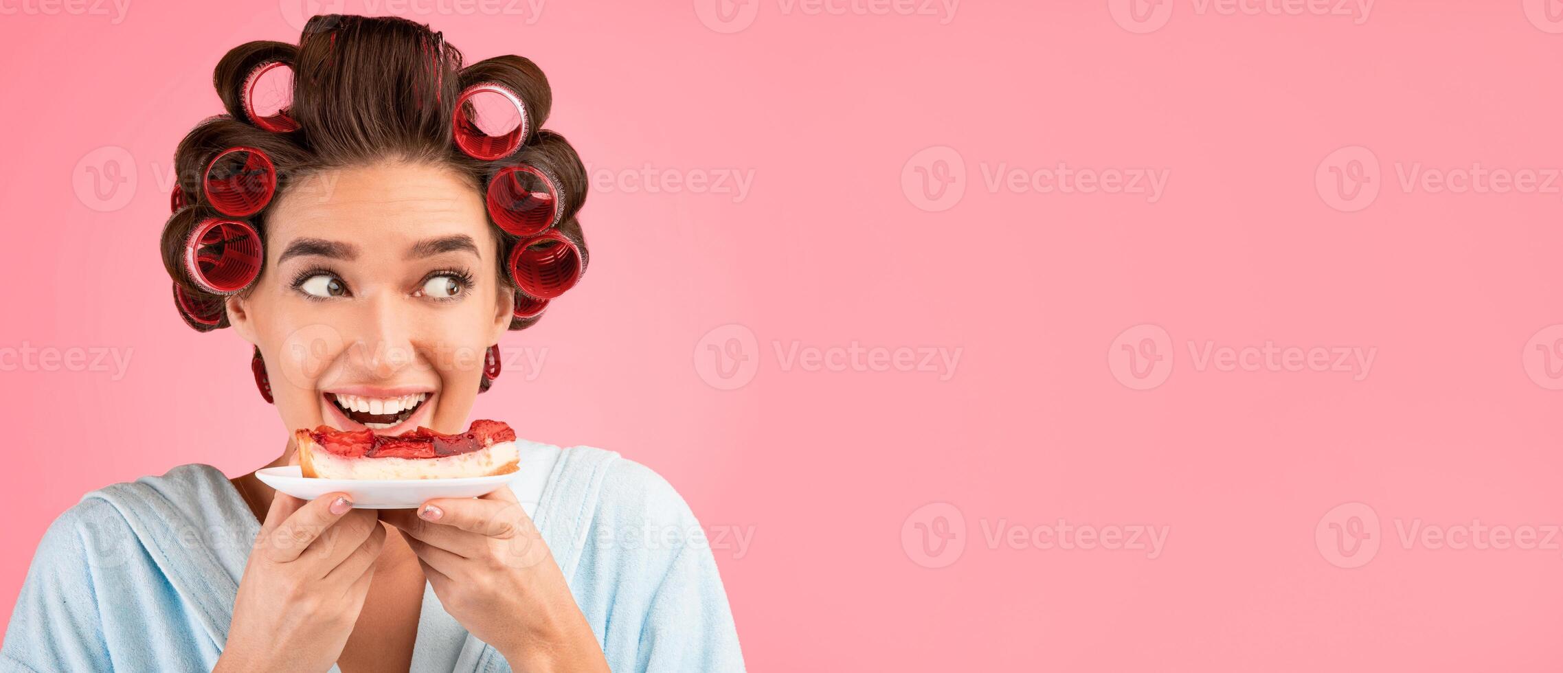 Cheat Meal. Hungry Girl With Curlers Eating Cake Enjoying Sweet Dessert Posing On Yellow Studio Background. Empty Space photo