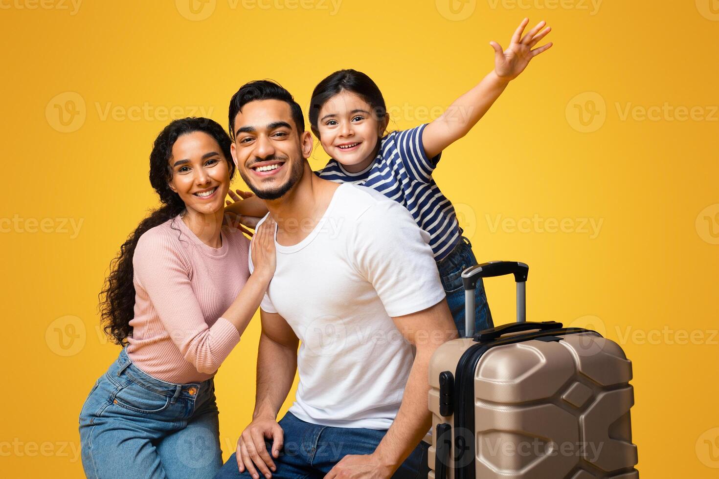 Family Travel Concept. Portrait Of Happy Arab Family Of Three With Suitcase Posing Over Yellow Background, Cheerful Middle Eastern Parents And Little Daughter Ready For Vacation Together, Panorama photo