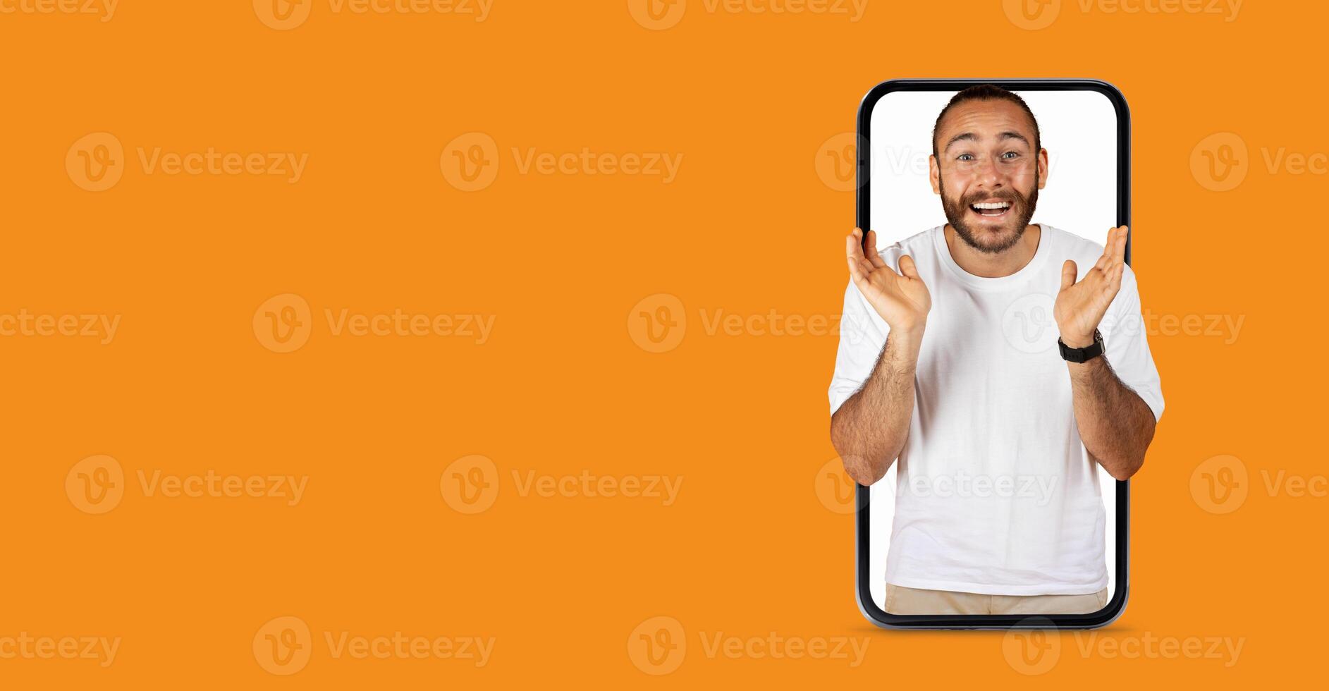 A person with a big smile is appearing to engage in lively communication through a large smartphone screen. The lively expression conveys excitement, enhancing the vibrant orange background. photo