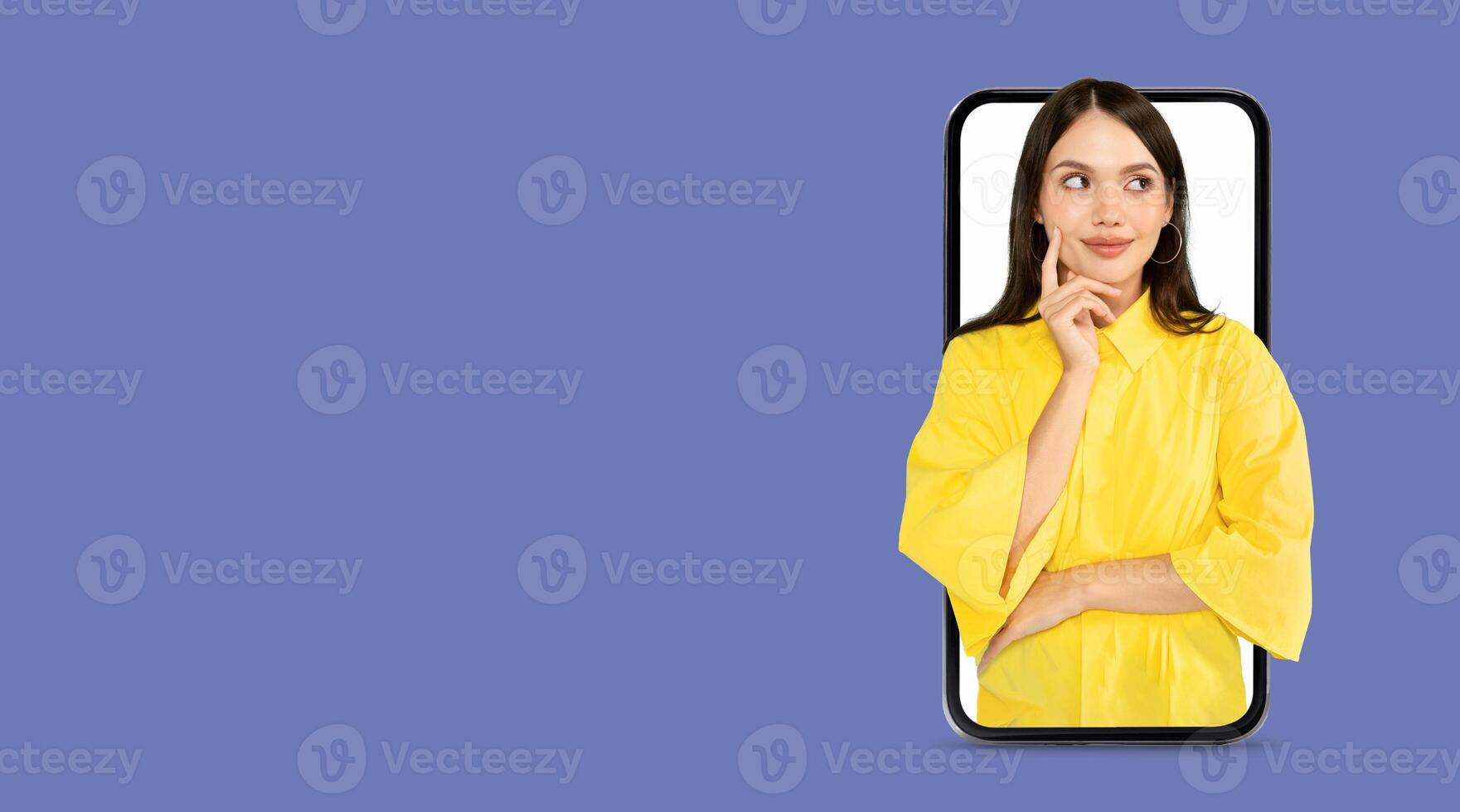 A young woman in a yellow top appears to be deep in thought as she interacts with a smartphone featuring a large screen. The background is a solid color, providing a modern feel. photo