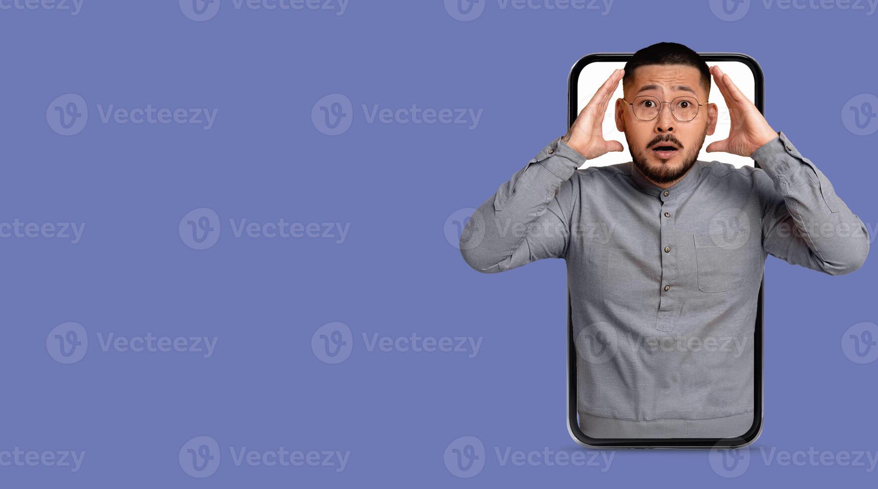 A person appears to be shocked or surprised, holding their head inside a large smartphone frame. This moment captures the impact of technology on communication and social interaction. photo