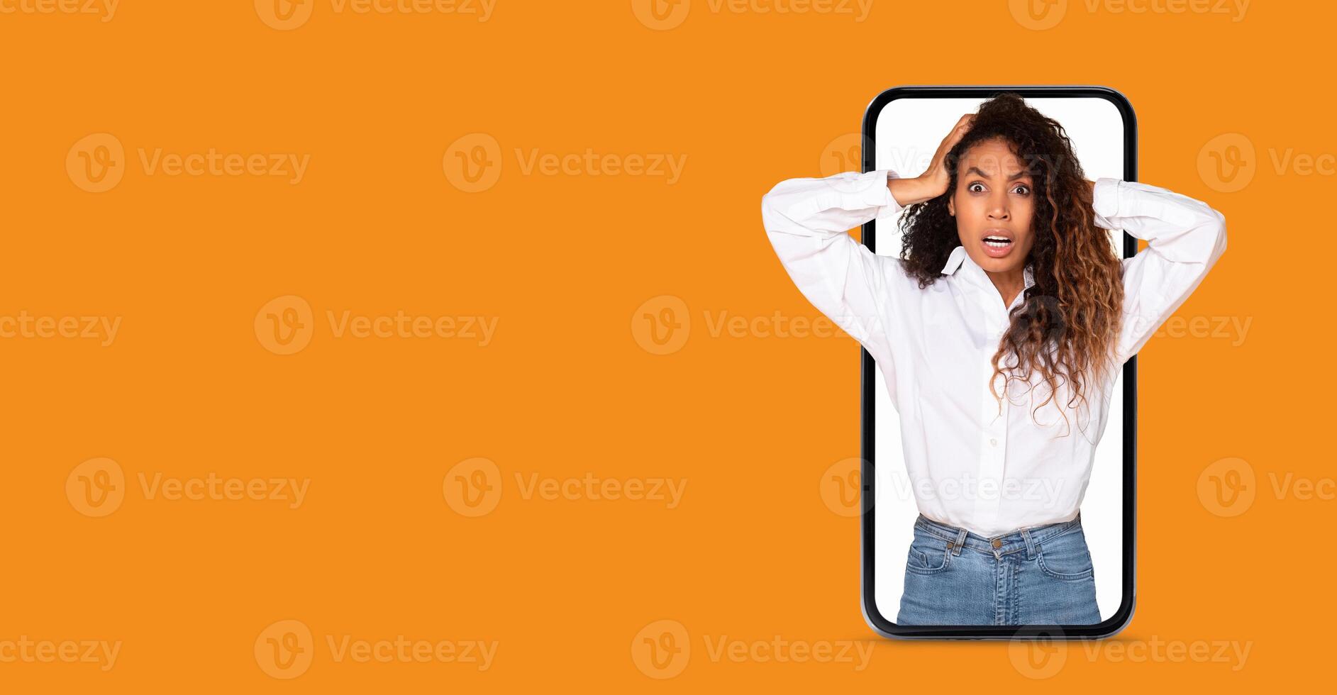 A woman with curly hair expresses surprise while holding her head in disbelief. She interacts with a large smartphone screen, conveying her reaction to shocking news or social media updates. photo