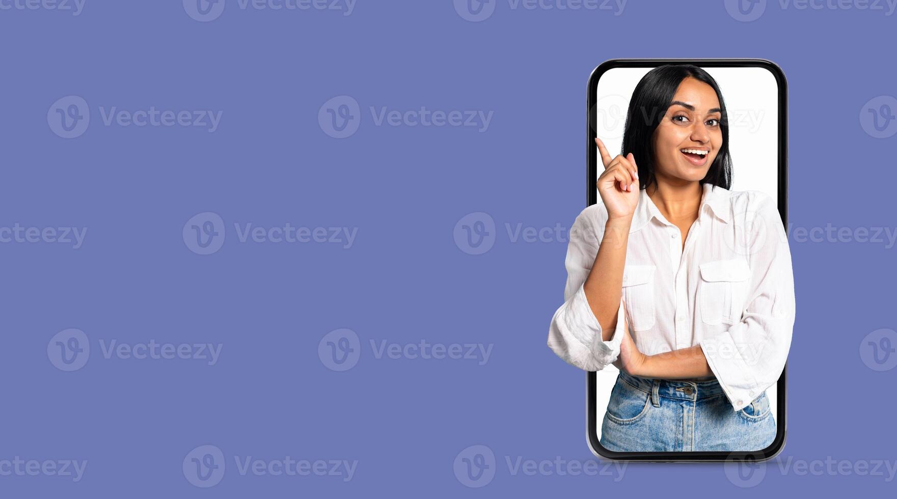 A young person with a friendly expression is gesturing while holding a smartphone. The background features a solid color, emphasizing the connection to social media and communication technology. photo