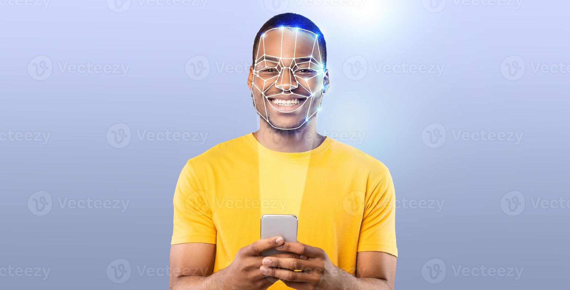 A young man with a cheerful expression uses his smartphone to engage in face recognition technology. The background is a simple gradient, emphasizing the modern tech experience. photo