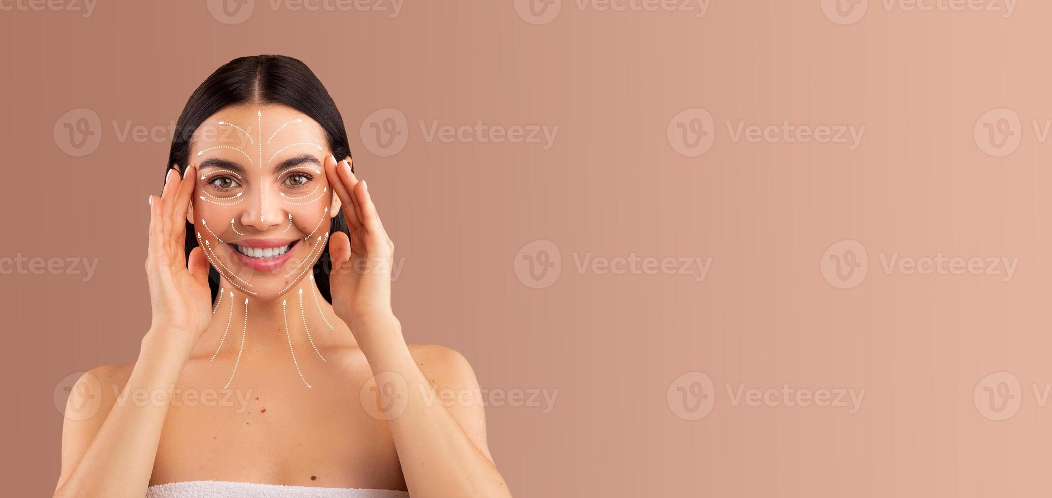 A woman enjoys a relaxing skin care routine, applying a facial treatment to enhance her beauty. She smiles while pampering herself in a peaceful setting with soft tones. photo
