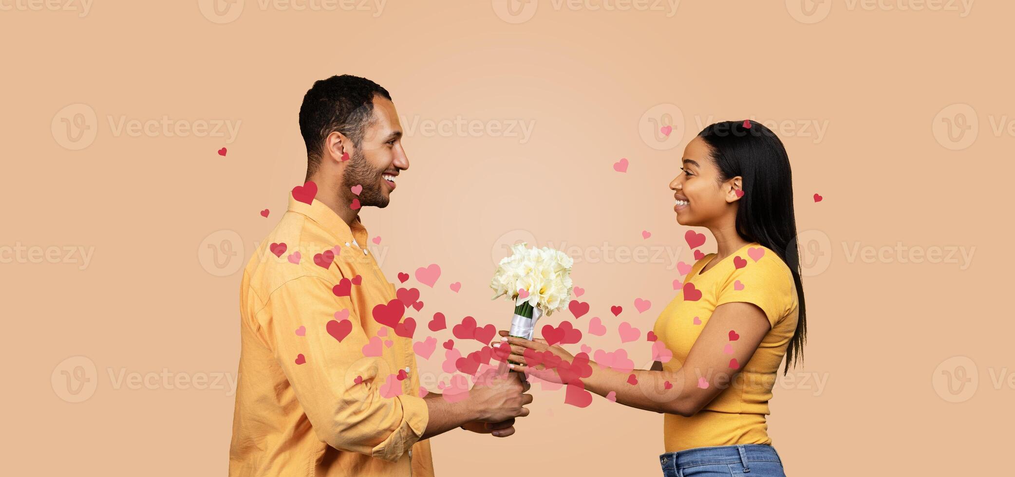 Black couple shares a loving moment, exchanging flowers while surrounded by heart graphics. Their smiles and gentle gaze reflect their affection and celebration of love, perfect for Valentine's Day. photo