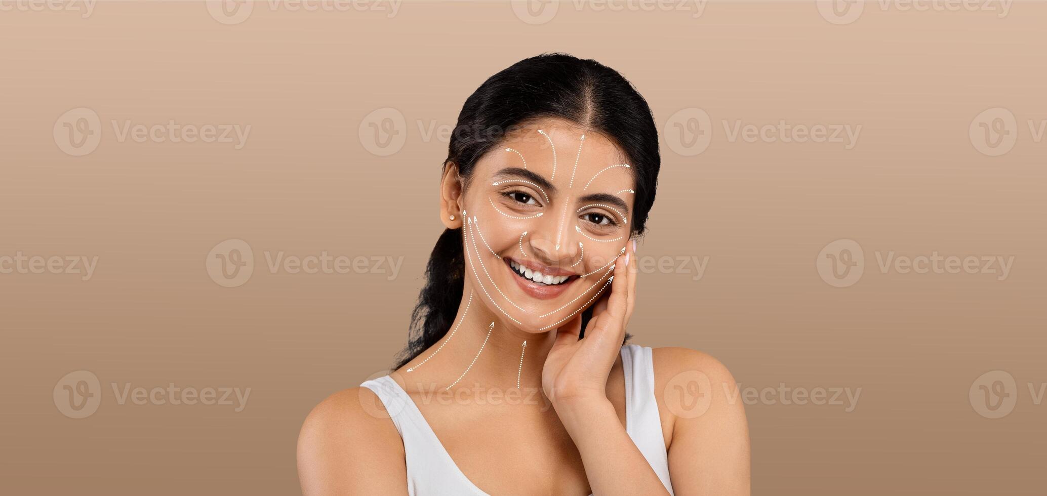 A lady is engaging in her beauty routine, smiling as she applies skincare products. The setting is isolated with a soft, neutral background that emphasizes her joy and pampering experience. photo