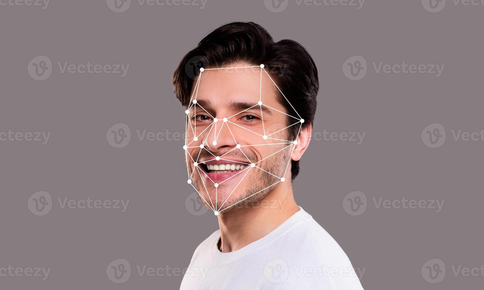 A man displays a joyful expression while facial recognition technology analyzes his features. The background is neutral, emphasizing the technological aspect of identification systems. photo