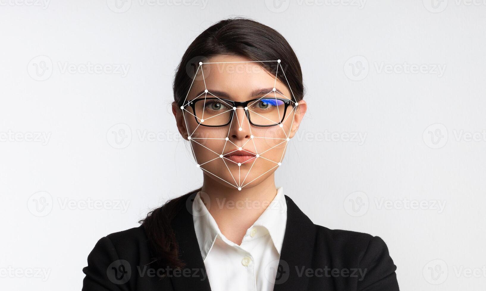 A professional woman poses confidently in a studio with her arms crossed. Advanced facial recognition technology is applied to her face, showcasing identification capabilities. photo