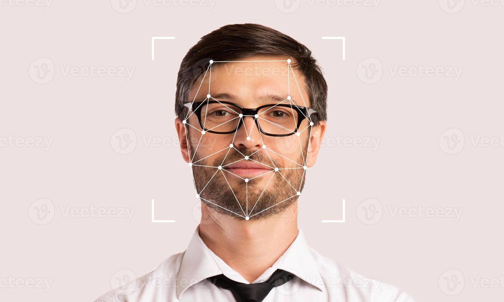 A man with glasses is standing against a neutral background while facial recognition technology highlights his features. This showcases advancements in ID technology and its applications. photo