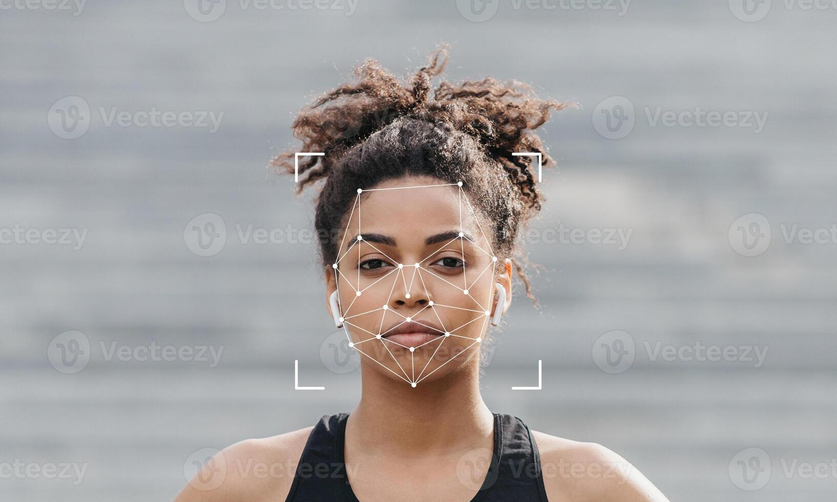A person stands in a relaxed posture, with their face framed by a technology overlay for identification. The background is softly blurred, creating a focus on the subject's features. photo
