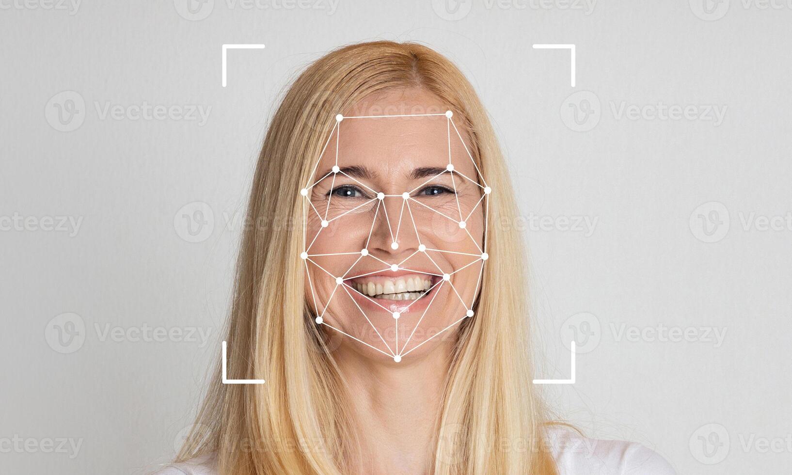 A woman with long blonde hair smiles as facial recognition technology analyzes her features. The background is a neutral color, emphasizing the focus on the subject's face and expressions. photo