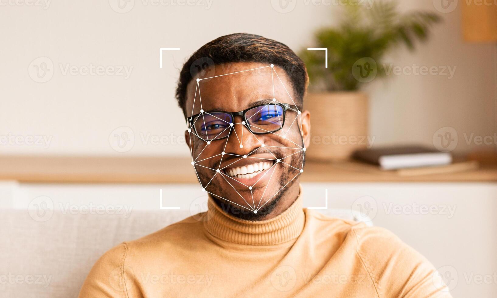 A person with glasses is smiling while sitting comfortably indoors. Facial recognition technology is being applied for identification purposes in a relaxed environment. photo